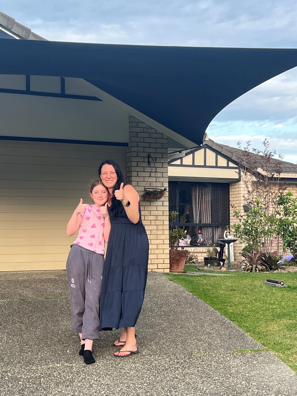 A lady and girl at home beneath their completed Shades2U carport
